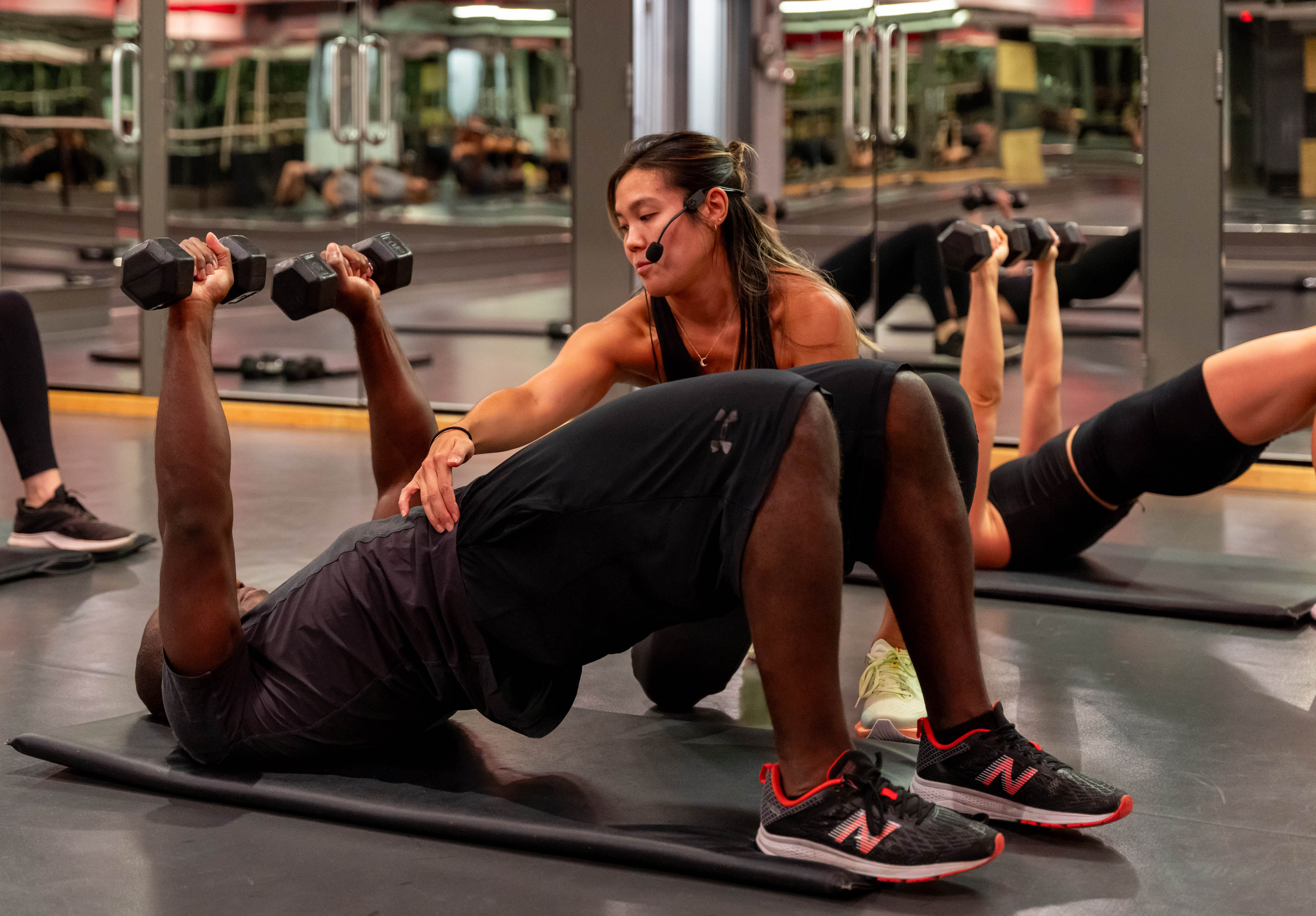 Young female instructor correcting fit male in a group fitness class at the Adelaide Club