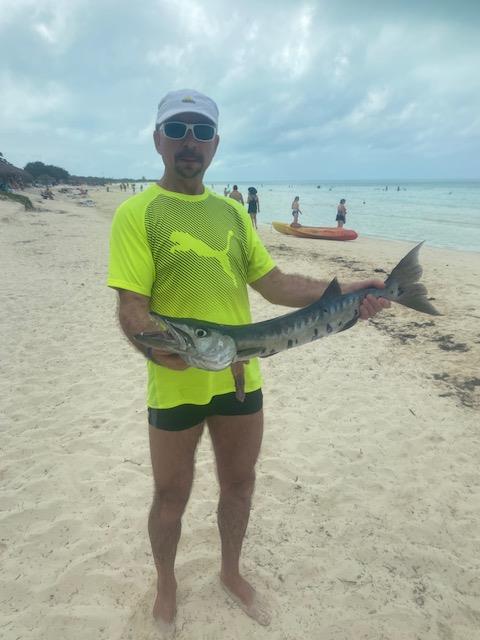 Bob Berezowski proudly holding a large catch on a Caribbean beach, showcasing the active outdoor lifestyle he embraces alongside his decades of dedication to health and wellness