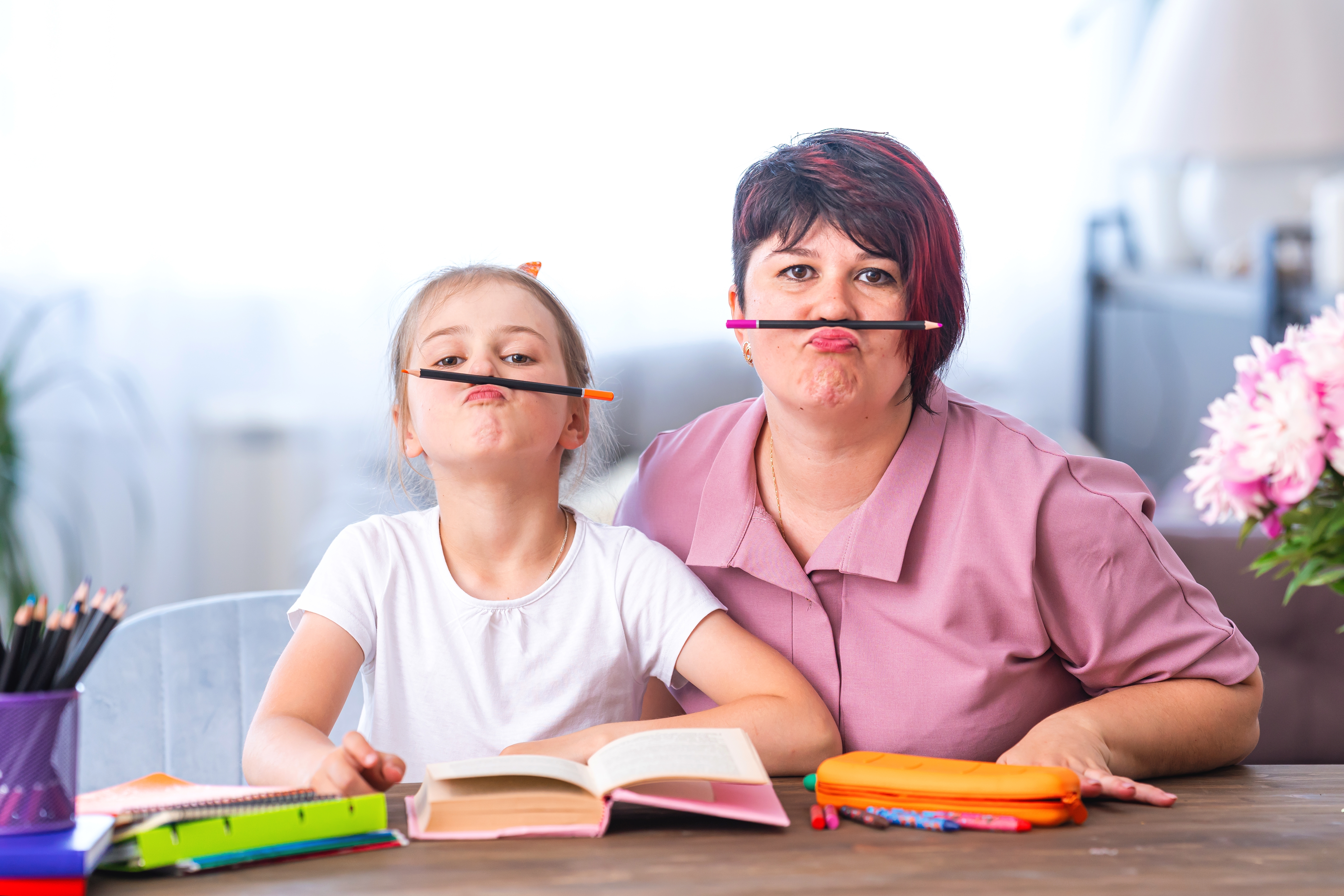 Mom and daughter being silly while studying at a table